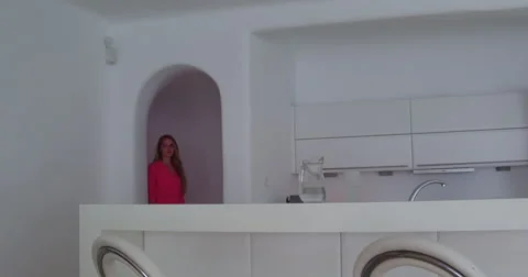 Blonde model enters kitchen and drinks fresh water 4K Stock Footage 68060319