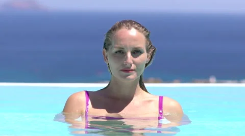 Blonde model goes underwater in pool with blue ocean background slow motion Stock Footage 68059265