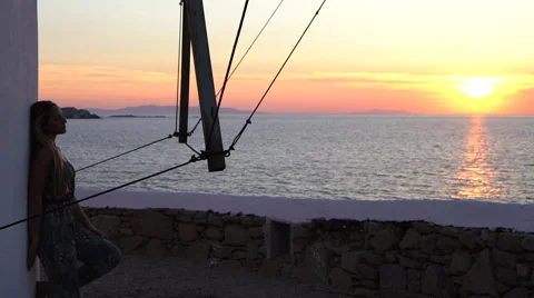 Blonde model leaning against windmill sunset silhouette mykonos greece Stock Footage 67971204