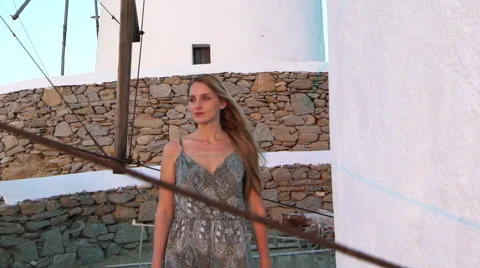 Blonde model leans against windmill sunset mykonos greece Stock Footage 67987013