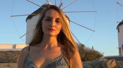 Blonde model looking into camera sunset windmill mykonos greece slow motion Stock Footage 67962390
