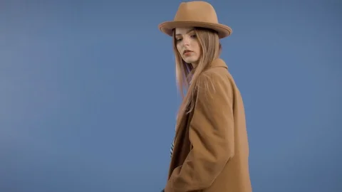 Blonde model rolling on deep blue background in large jacket Stock Footage 126113184