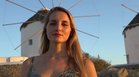 Blonde model smiles blur to focus with windmill in background mykonos greece Stock Footage 67998721