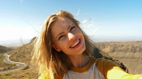 Blonde Model Smiling Taking Holding a Camera as She Takes a Selfie Video stock 114325292