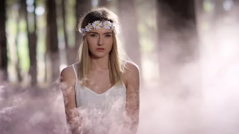 Blonde model staring at the camera in a forest with pink smoke Stock Footage 264011790