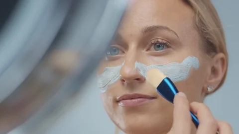 Blonde model in studio makes a cleansing facial mask Stock Footage 107517060
