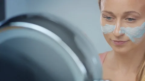 Blonde model in studio makes a cleansing facial mask Video stock 107517084