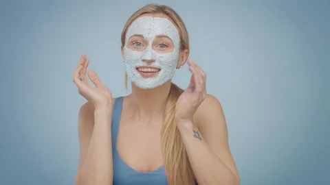Blonde model in studio makes a cleansing facial mask Stock Footage 107517160