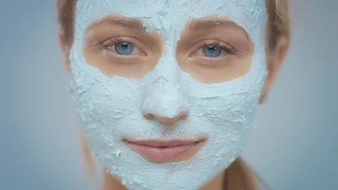 Blonde model in studio makes a cleansing facial mask Stock Footage 107517177
