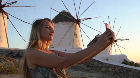 Blonde model takes selfie in front of windmills mykonos greece slow motion Stock Footage 68006525