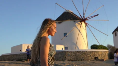 Blonde model walks in front of windmills at sunset mykonos greece slow motion Stock Footage 68003344
