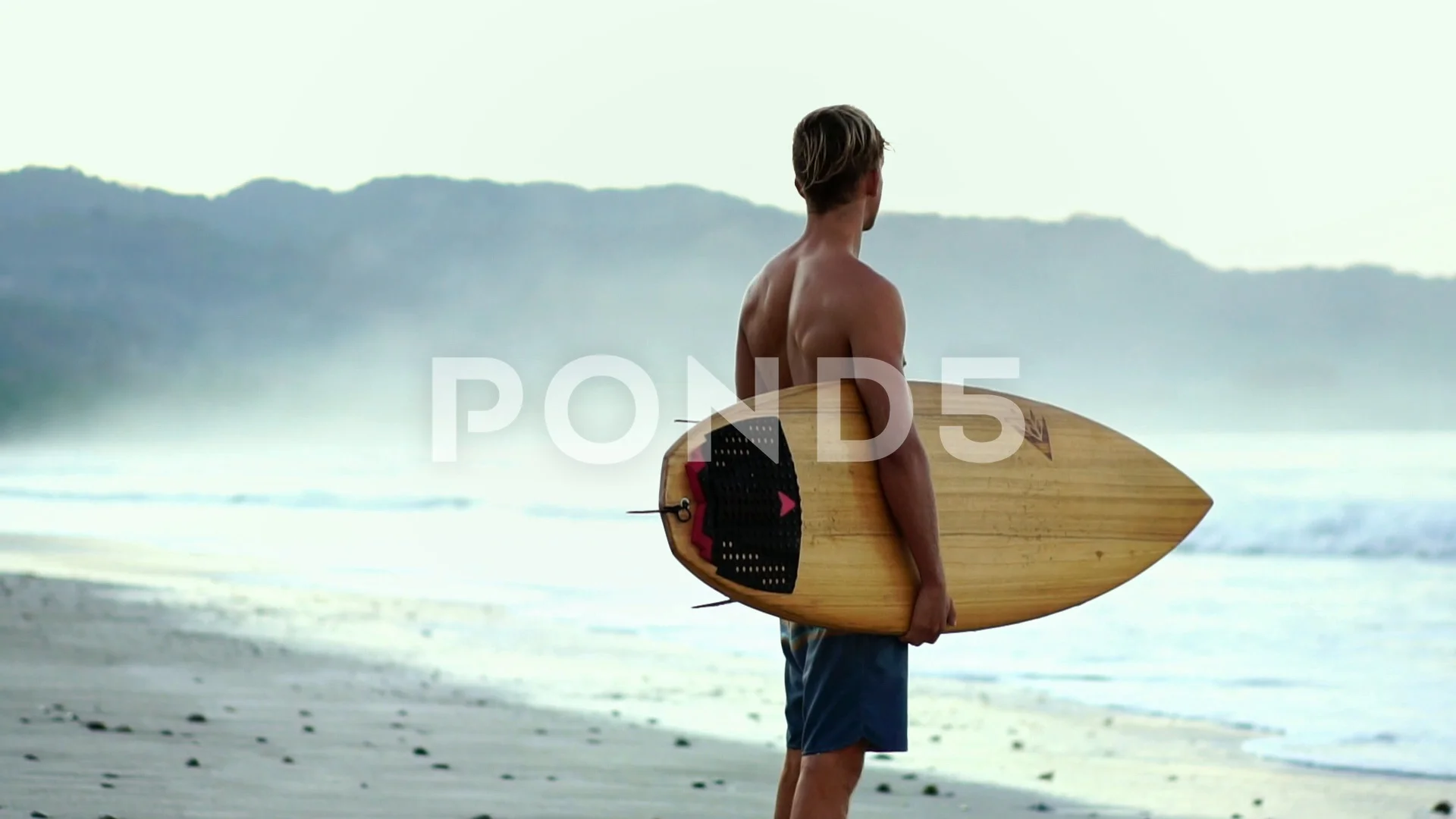 Blonde muscular surfer man on beach holding surfboard, sunrise scene slow  motion