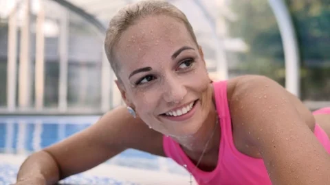 The blonde in a pink bathing suit laughs lying on the blue side of the pool Stock Footage 122222786