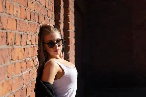 Blonde posing by the brick wall, closing her eyes and turning her head toward 写真素材
