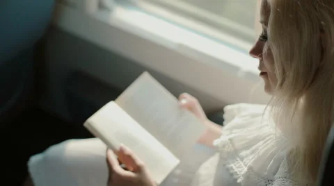 Blonde reading a book in the train Stock Footage 59799260