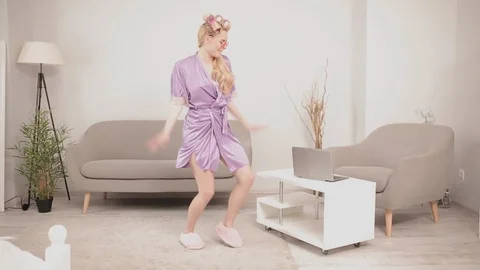 Blonde on self-isolation dances to active music, dressed in bathrobe and curled Stock Footage 130130452