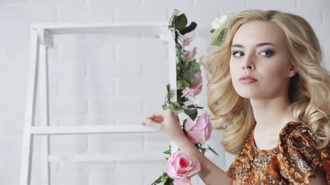 Blonde sexy posing in a white room, decorated with pink flowers. Stock Footage 71502009