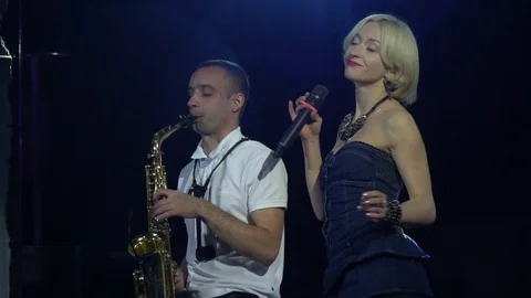 Blonde singer is dancing while her partner is playing on saxophone Stock Footage 111197148