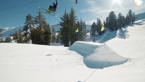 Blonde skier does crazy trick off jump in sunny mountains sprays snow Видео 103822600