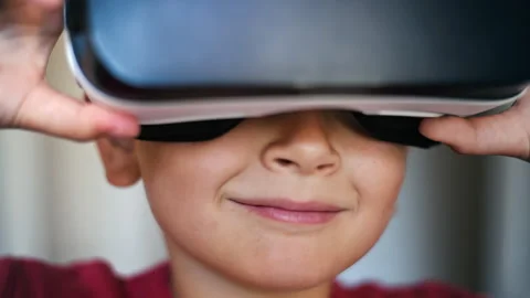 Blonde small boy is looking into the camera and putting on VR headset Stock Footage 250364011