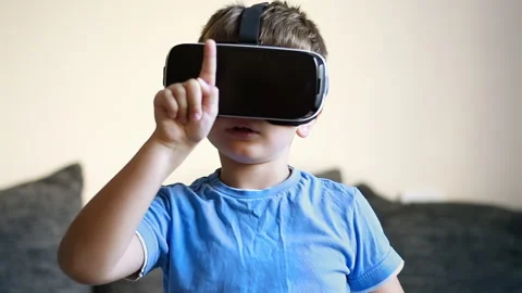 Blonde small boy wearing a virtual reality headset at home. Looks around in Stock Footage 250364045