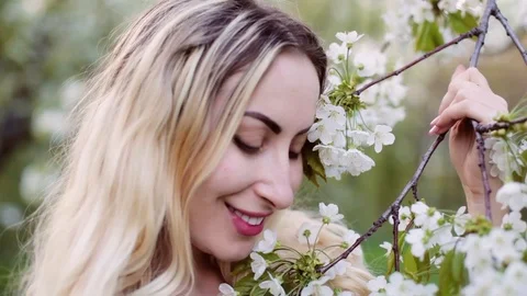 Blonde sniffs flowering trees in spring. Stock Footage 107775003