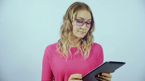 The blonde is standing and looking at the tablet. Video stock 84265516