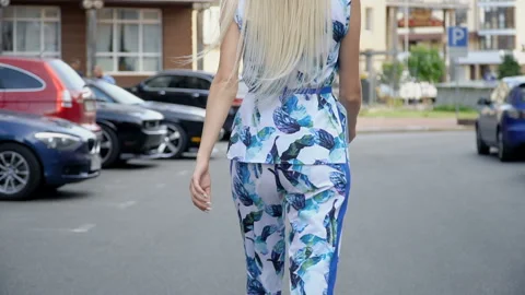 Blonde in a summer suit posing in the parking lot. Camera wiring. Women's walk Stock Footage 114796652