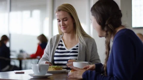 Blonde Takes Bite Of Her Avocado Toast, She And Her Friend Both Laugh Stock Footage 85762210
