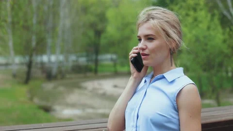 Blonde talking on a cell phone in the park Stock Footage 196683992