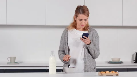 Blonde using mobile morning on the kitchen Stock Footage 154375482