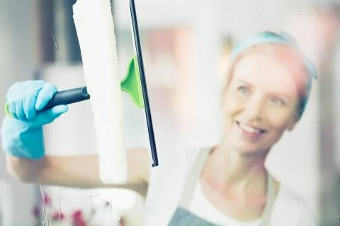 Blonde woman is cleaning window Stock Photos