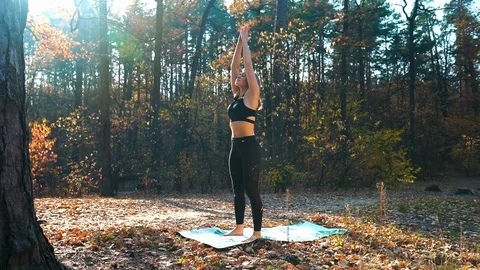 Blonde woman does complex of yoga exercises on mat in forest Stock Footage 124636713
