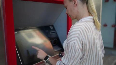 Blonde woman entering PIN code while using ATM machine outdoors. Secure ban.. Stock Footage 339780285