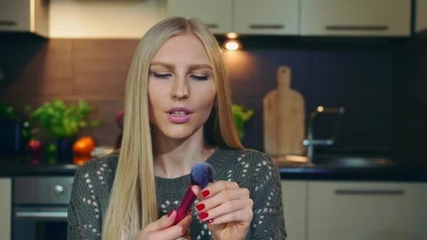 Blonde woman explaining makeup brush in modern kitchen Stock Footage 340275593