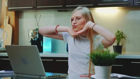 Blonde woman gesturing while seated at kitchen counter with laptop Video stock 342307084
