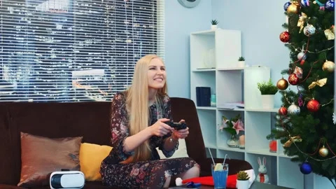 Blonde woman playing with gaming controller in modern living room Stock Footage 340961648