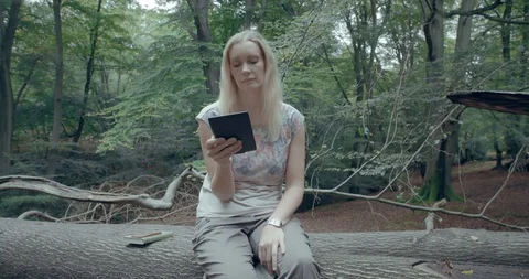 Blonde woman reading tablet in forest Stock Footage