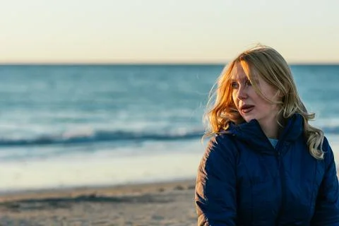 Blonde woman with relaxed expression on a beach during sunset Stock Photos