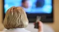Blonde woman with remote control switch tv channels HD Footage
