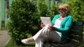 Blonde woman sits on the bench and communicates via Tablet-PC HD Footage
