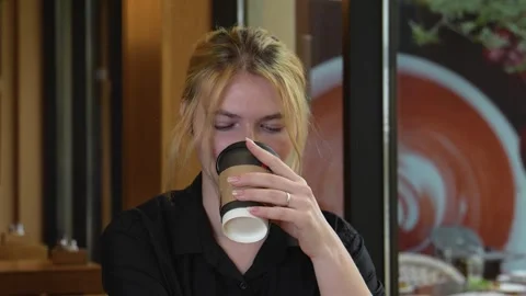 A blonde woman is smiling while drinking from a coffee cup Stock-Footage 319826398
