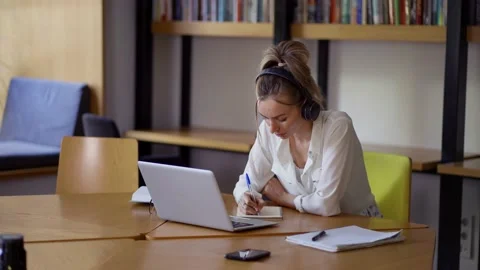 Blonde woman study at distant learning at library, taking notes Video stock 160326162