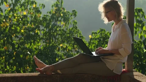 Blonde woman using laptop while sitting on the rooftop in sunlight. Stock Footage 236827412