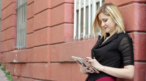 Blonde woman using tablet pc on a street Stock Footage 35009684