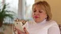 Blonde woman with white smartphone sits on the couch and listening to music HD Footage