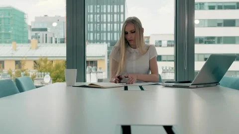 Blonde woman writing notes at table in modern office conference room Stock Footage 340256670