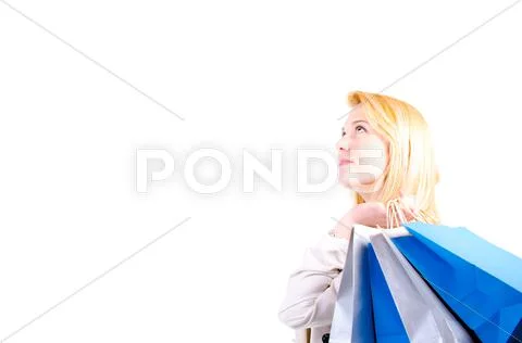Blonde young woman holding shopping bags looking upwards at copyspace Stock Photos