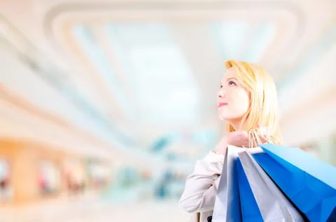 Blonde young woman holding shopping bags looking upwards at copyspace Stock Photos