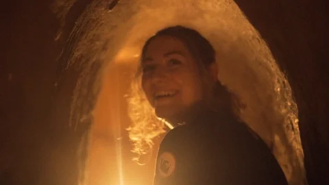 Blonde young woman inside tiny underground Tunnel from Vietnam war smiles into Video stock 87265618